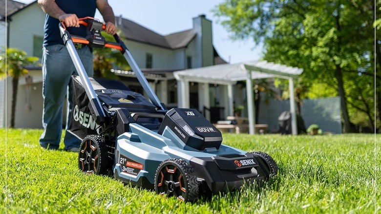 Person using the SENIX X6 60V Max 21" Self-Propelled Mower outside on a lawn.