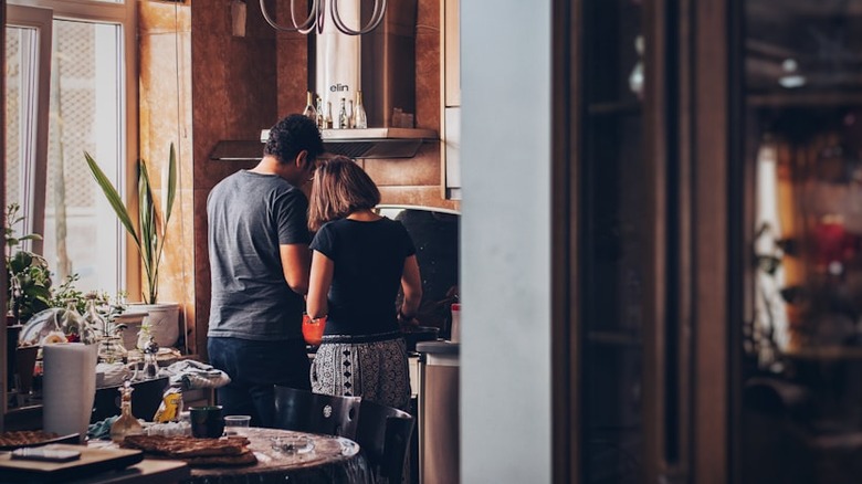 man and woman standing in kitchen with dining table