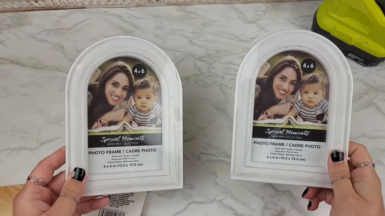 Person holds two Dollar Tree picture frames