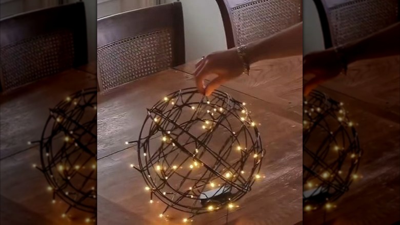 A woman holding a DIY orb light made from Dollar Tree items