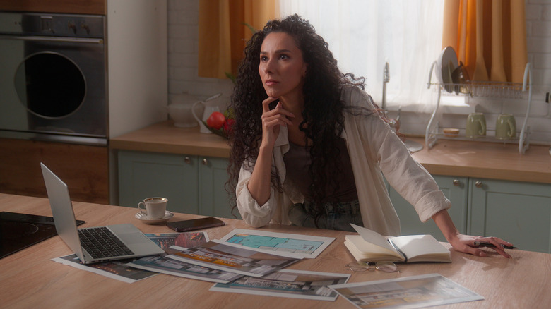 Person sitting in kitchen with plans for a remodeling project