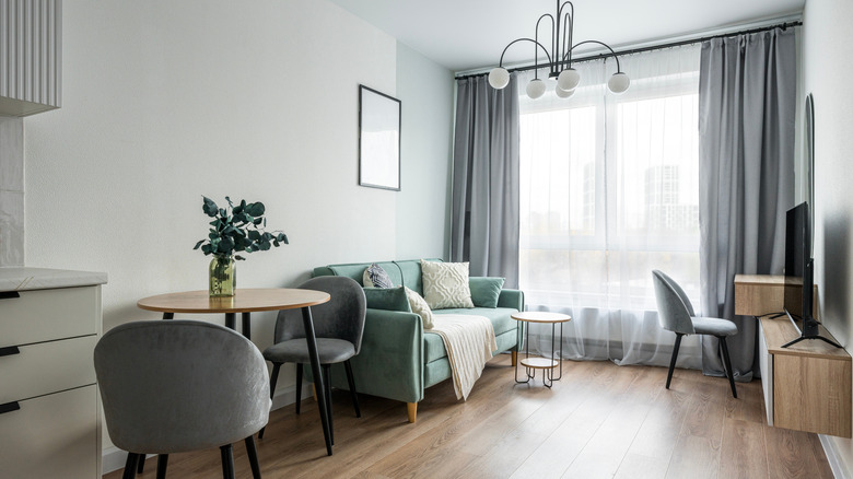 Narrow living room with oversized light fixture and floor to ceiling drapery