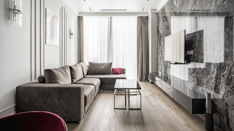 Modern narrow living room with vertical elements to draw the eye up, including floor-to-ceiling drapes, wall sconces, and molding