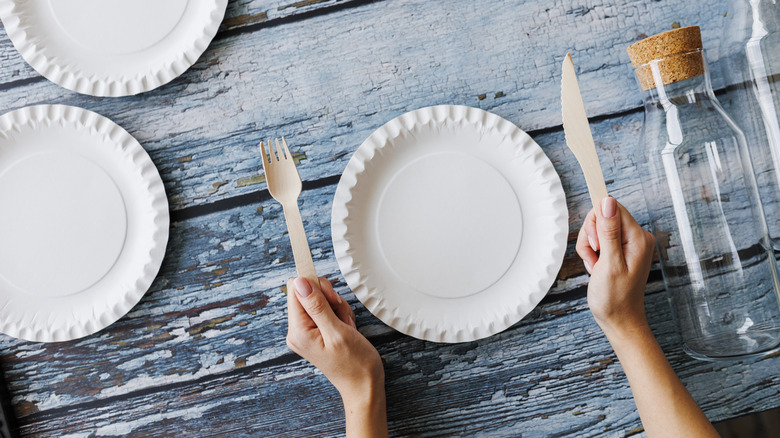 Disposable paper plates on a table with cutlery