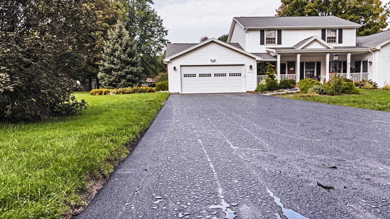 Freshly surfaced asphalt driveway in front of white garage