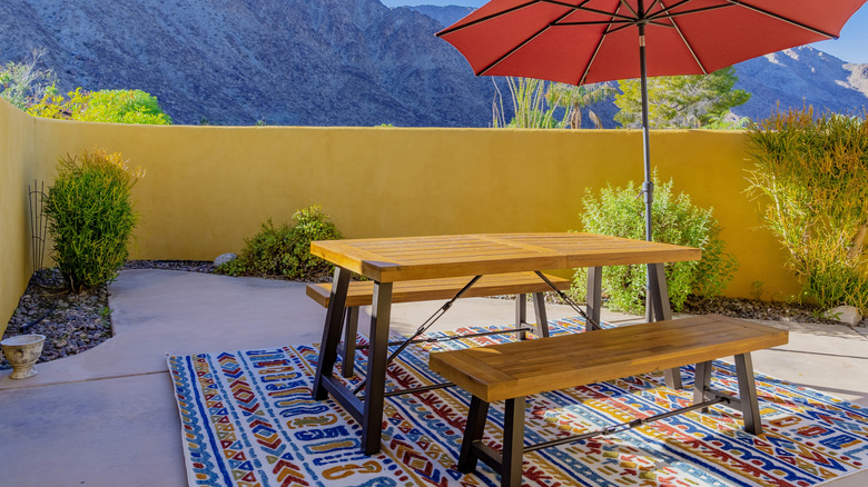 patio with bright rug, table, and umbrella