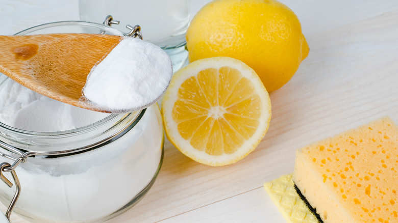 Baking soda, lemons, and sponges sit on a kitchen countertop