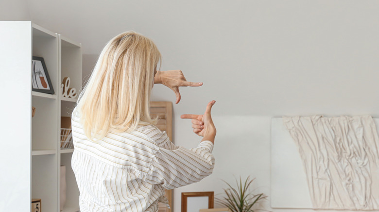 Woman looks at blank wall, planning what to do with it
