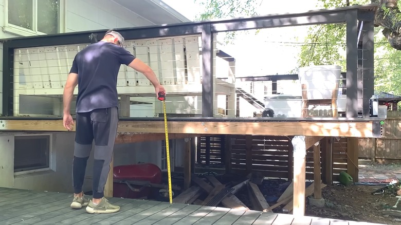 Man measuring outdoor backyard deck for DIY privacy screen project