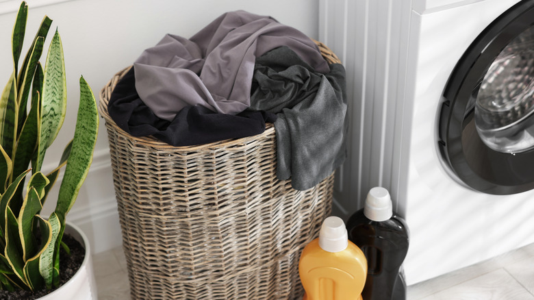 Full laundry basket of dirty clothes next to washing machine