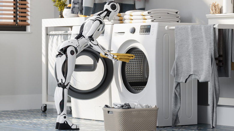 A robot loads laundry into a washing machine.