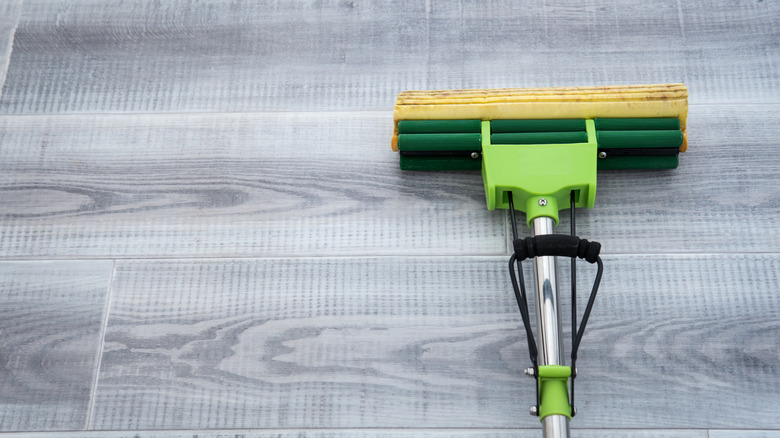Close-up of a sponge mop sitting on a gray linoleum floor