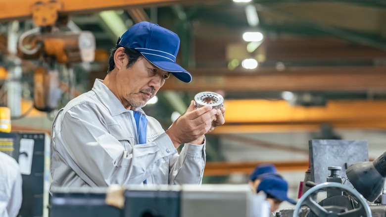 Factory worker inspecting metal part