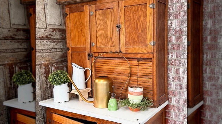 A Hoosier cabinet being used as an indoor potting bench in a home