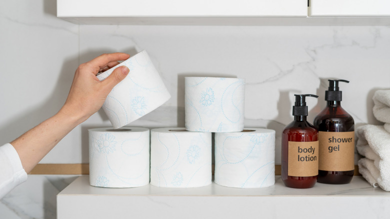 Person placing toilet paper on a shelf