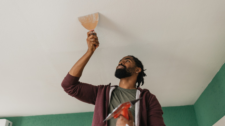 Young man working on his ceiling