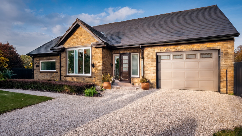 A brick house with a large gravel driveway