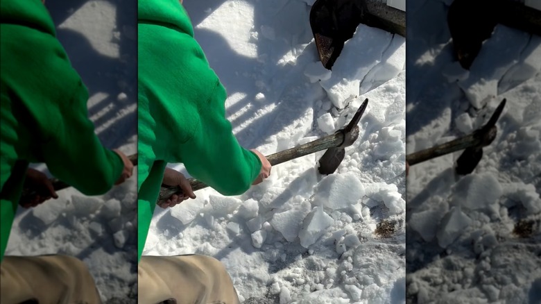 person breaking ice with pickaxe