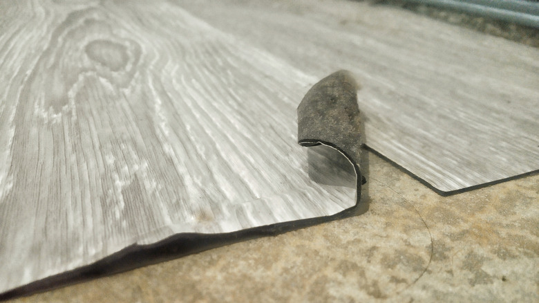A gry wood grain print vinyl sheet curling at one edge