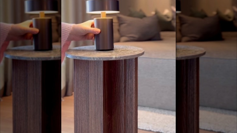 Hand placing lamp on side table