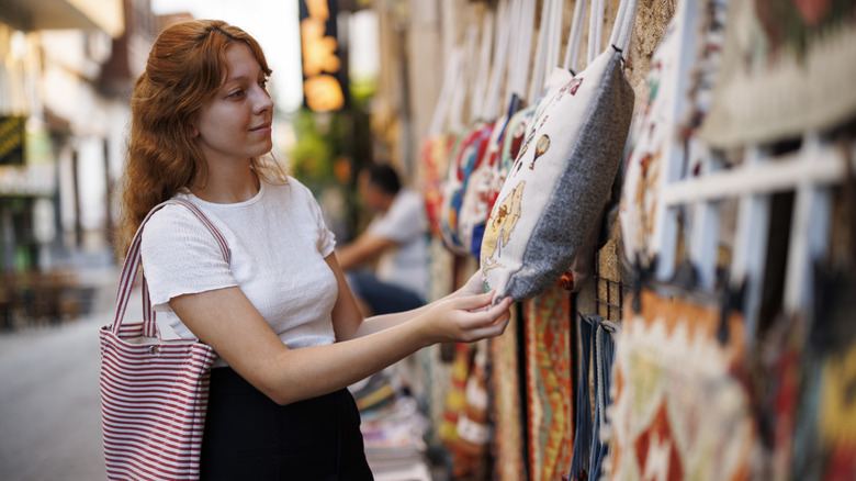 Woman shopping for handmade pillows and textiles at a street market