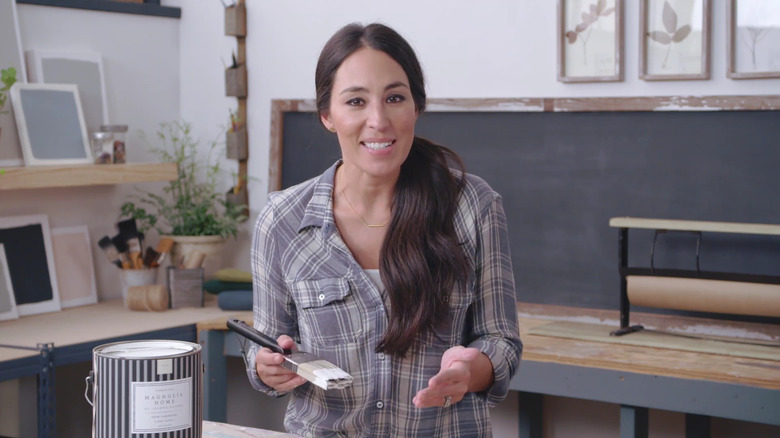 Joanna Gaines smiling at camera while holding a paintbrush