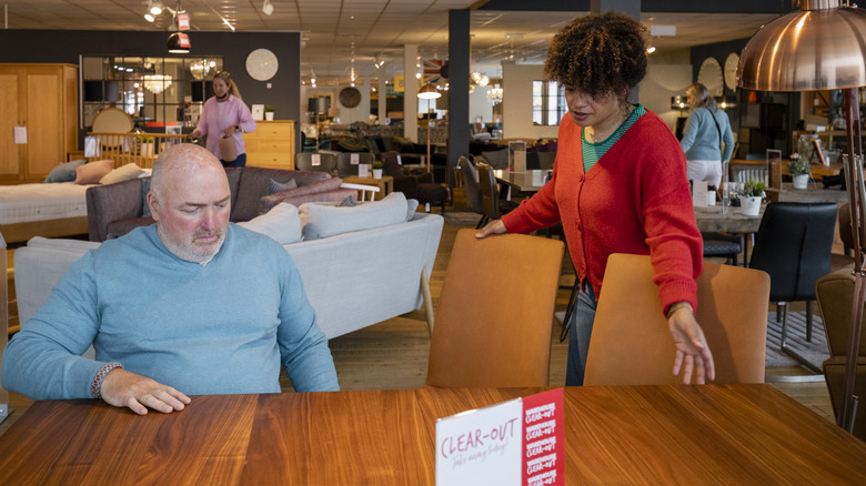 A woman is helping a man buy a wood table