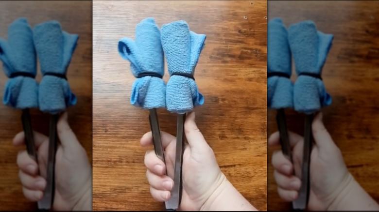 Pair of tongs with cloths wrapped around the end.