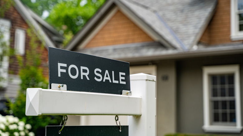 A for sale sign posted in front of a bungalow.