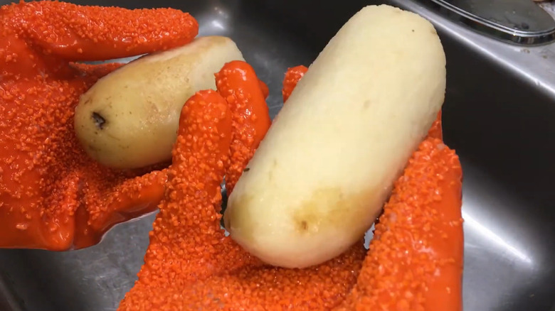 Person using potato peeling gloves on a potato