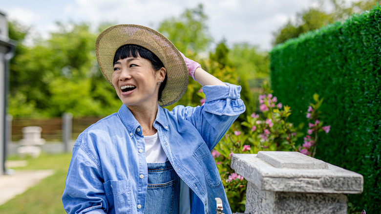 A woman smiles by her front lawn