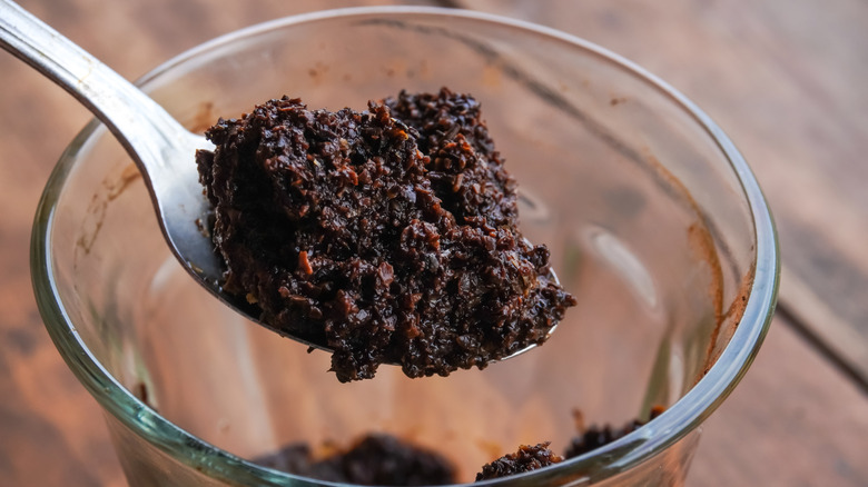 Spoon holding coffee grounds scooped from a cup