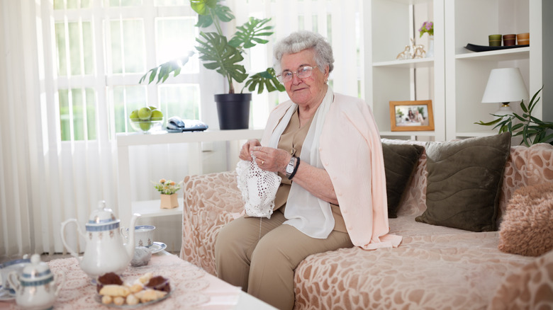 Elderly woman crocheting on a couch