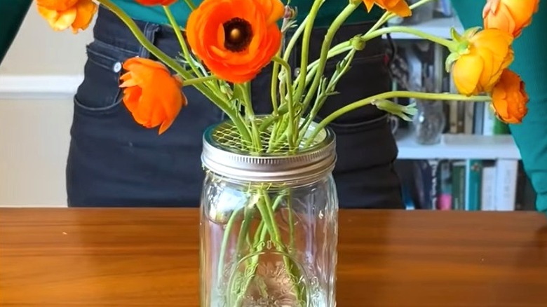Floral arrangement in Mason jar with mesh over jar's mouth