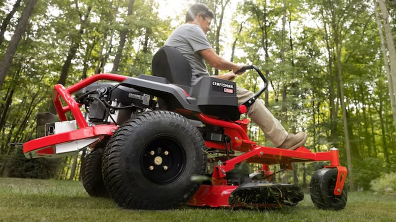 A man riding a Craftsman Z5400 Zero-turn riding lawn mower is surrounded by trees