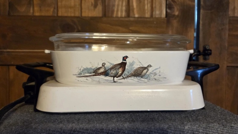 A Corningware Gamebirds casserole on a warming stand