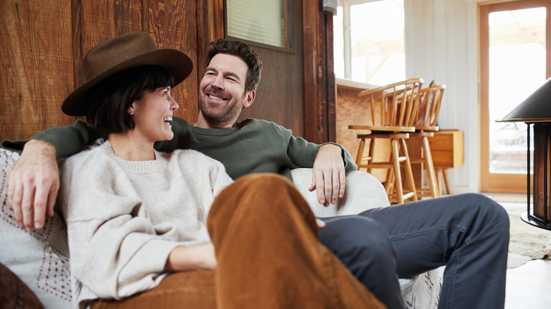 A couple smiling on the sofa while wearing a cowboy hat