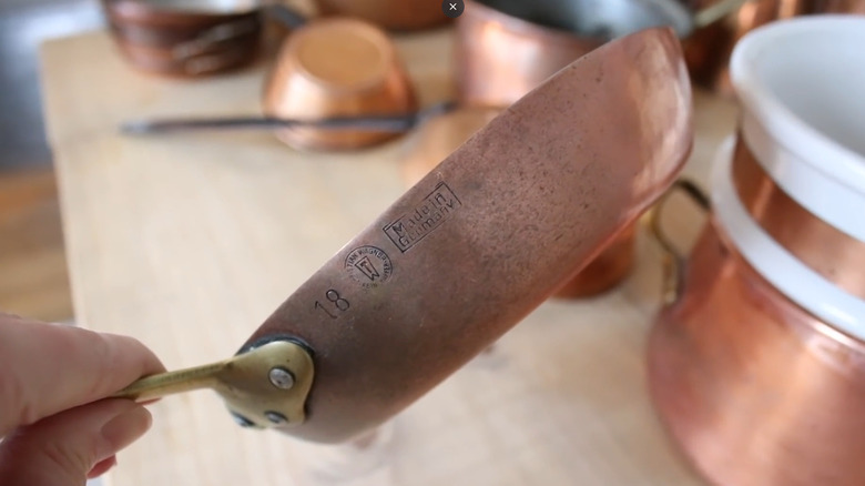 Woman identifying vintage copper pan by stamped side