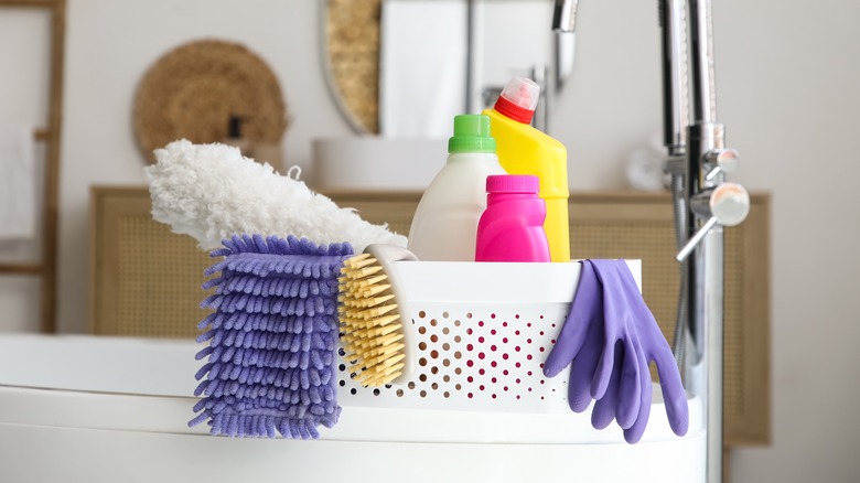 a bucket of cleaning supplies sitting on a bathtub