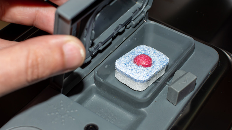 Empty pre-wash compartment next to dishwasher tablet