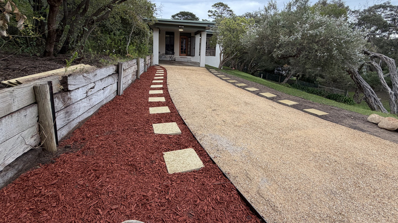 Wide angle shot of a modern home with gravel driveway, red mulch, and stepping stones