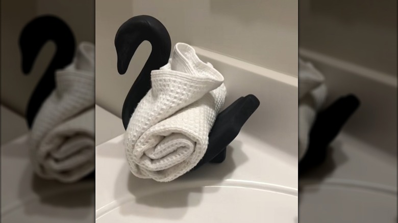 Black ceramic swan on a bathroom countertop with a rolled white towel in it