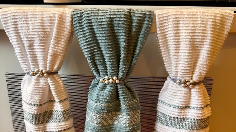 Three kitchen dowels draped over the handle of a stove and held in place with hair ties