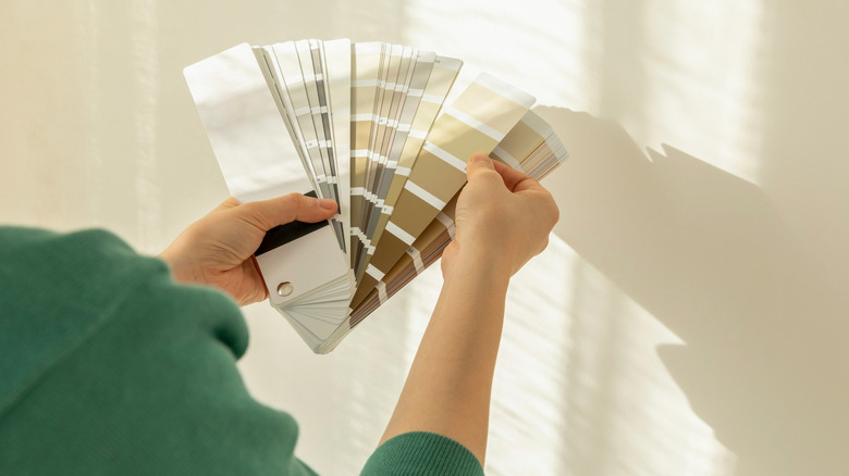 Someone looking at a bundle of neutral paint color swatches