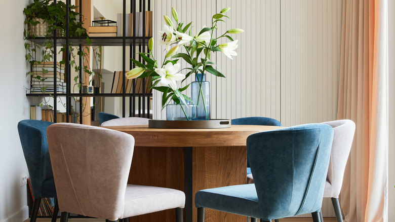 modern dining room with velvet upholstered chairs, a textural wall finish, and soft drapery