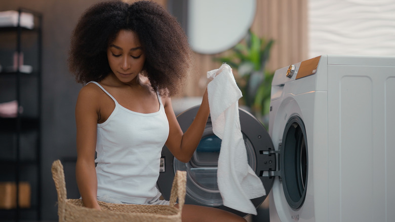woman adding towel to dryer