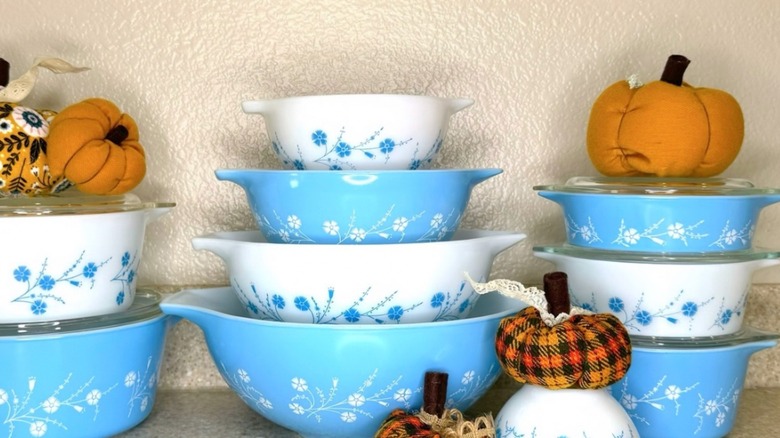 A collection of blue dianthus Pyrex cookware is accented with small pumpkins.