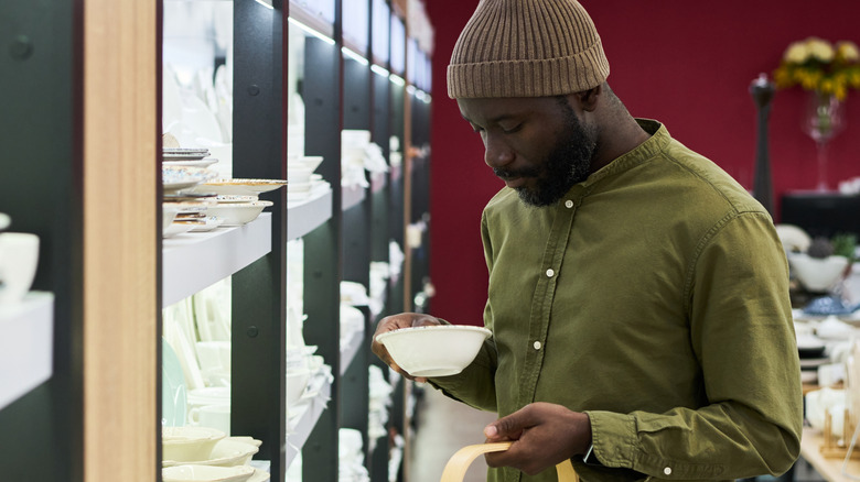 A man looks at a vintage dish in a shop.