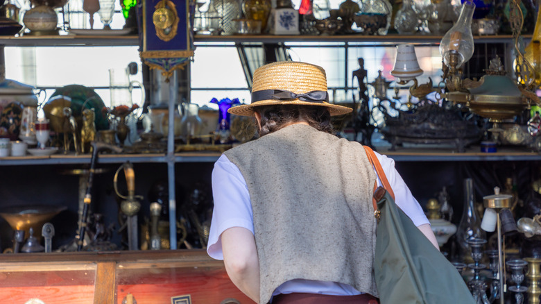 A person wearing a straw hat browses at a vintage store.