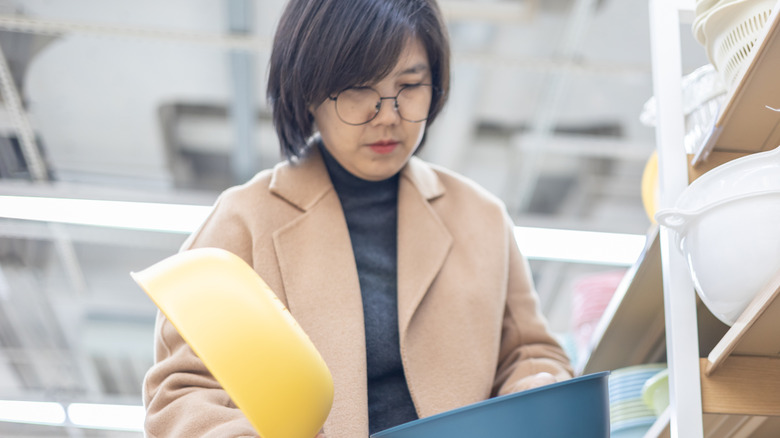 A woman looks at yellow and blue dishes in a store